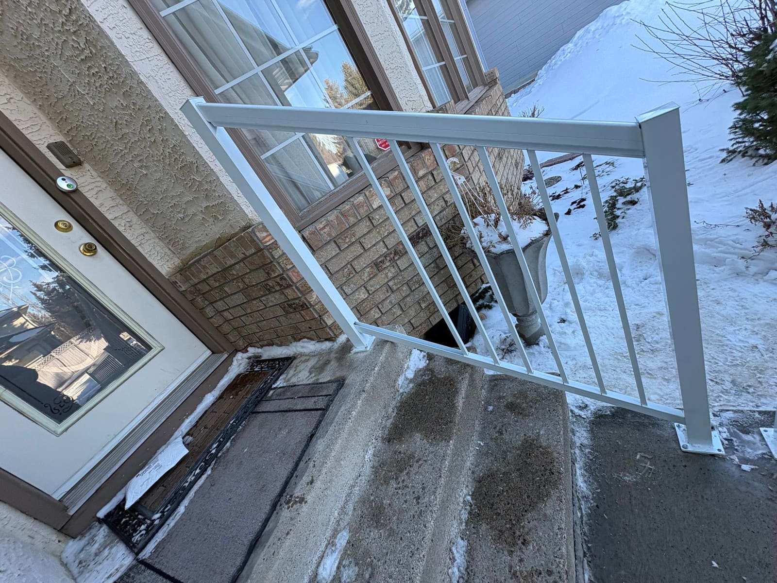 A white powder-coated aluminum handrail with horizontal rails at a home's front entrance