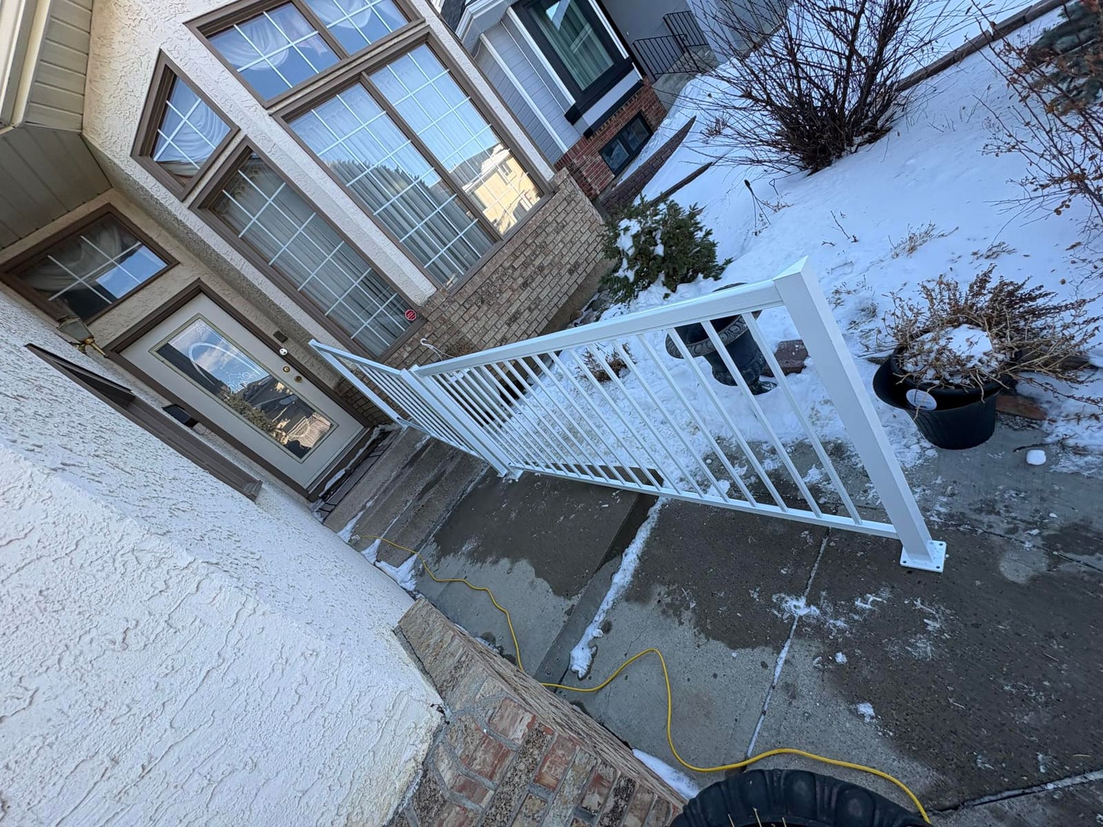 A white aluminum picket handrail installed the full length of a home's front stairs