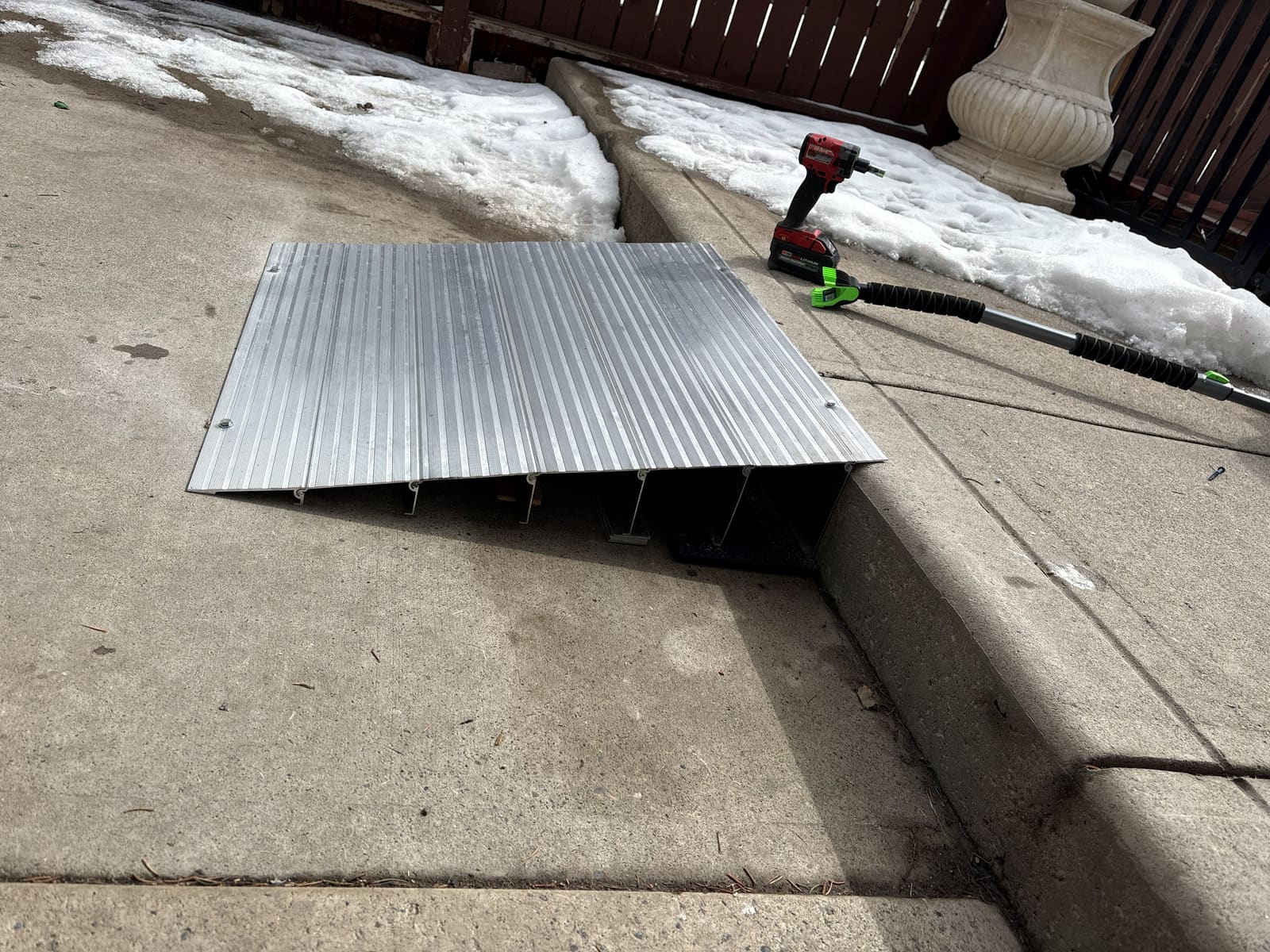 An aluminum threshold ramp fitted over a raised step at a home entrance