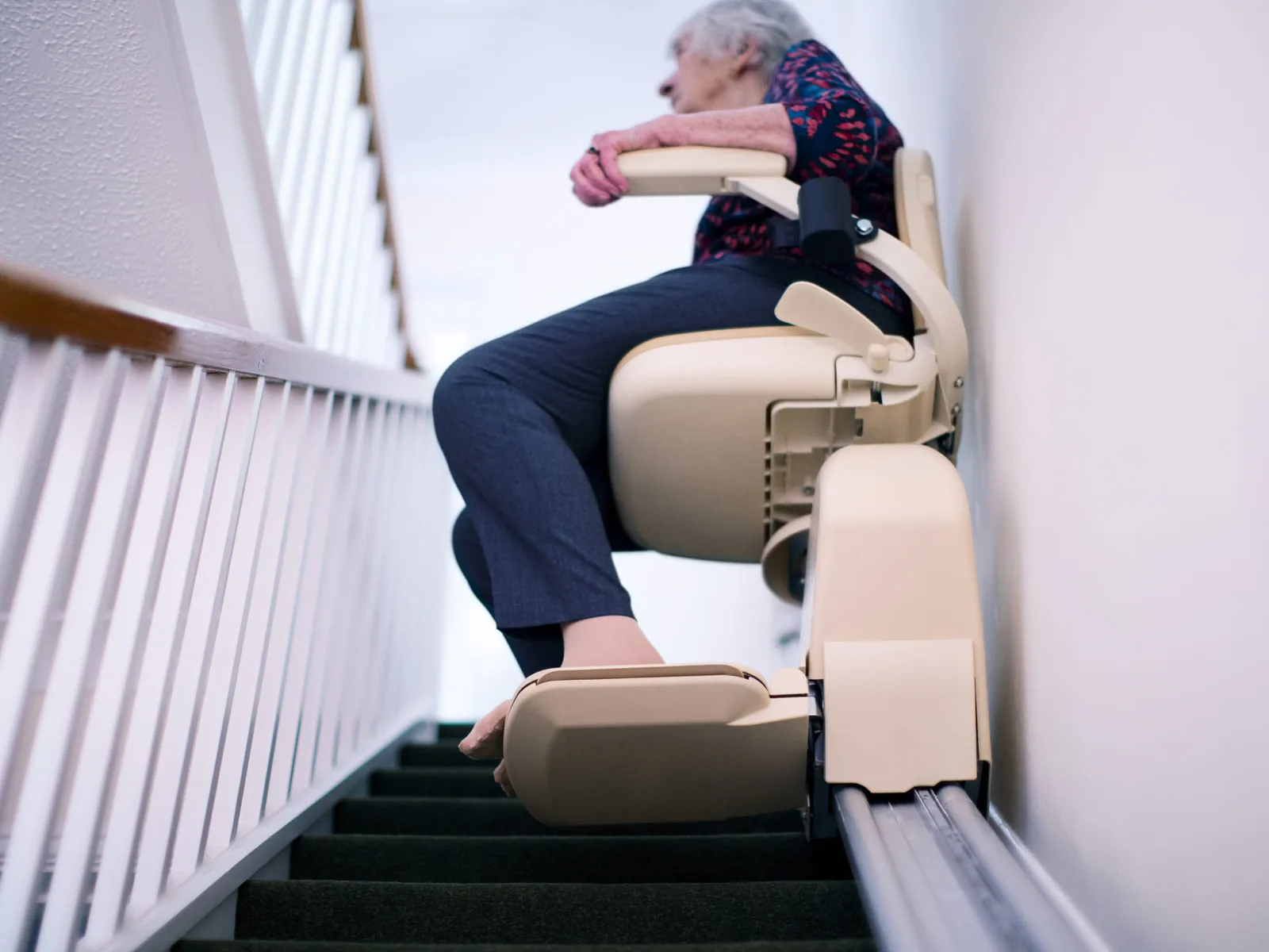 A senior riding a stair lift down a domestic staircase